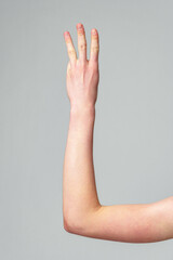 Human Hand Raised in a Gesture Against a Plain Grey Background