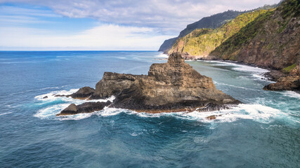 Obraz premium The majestic green mountains of Madeira rising above the crystal-clear, azure ocean; the natural beauty and wilderness of the island are breathtaking.