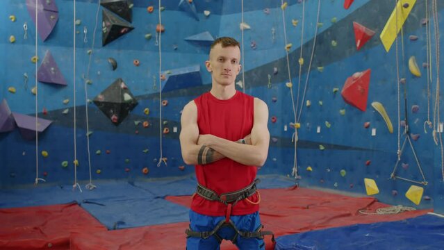 Portrait of confident athlete with prothetic leg holding arms crossed and posing for camera in climbing gym