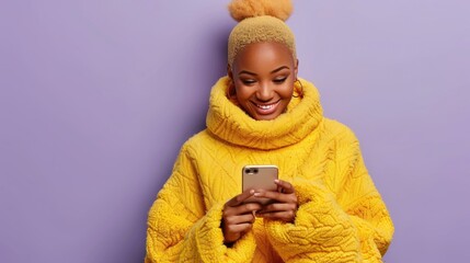 A woman in a yellow sweater is smiling and looking at her phone