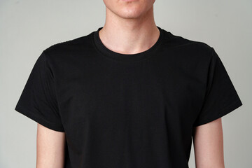 Young Man Wearing a Plain Black T-Shirt Against a Gray Background