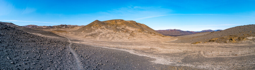 Fototapeta na wymiar Panoramic view from Askja volcano in the lifeless volcanic desert in Highlands, with stones and rocks thrown by volcanic eruptions, Iceland, summer, blue sky.
