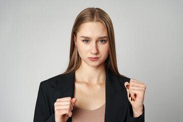 A young woman stands confidently against a neutral background with clenched fists
