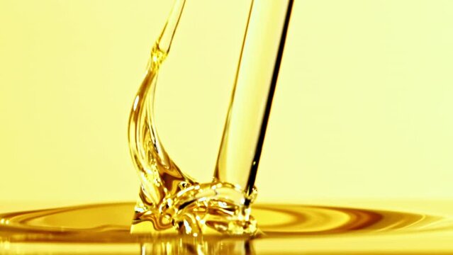 Super slow motion olive oil pours in a stream with splashes. High quality FullHD footage