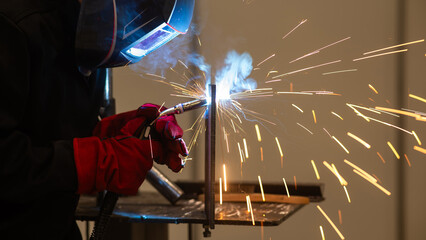 A man learns the craft of welding on a sample. 