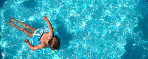child boy  with inflatable ring swims in the pool. copy space. banner