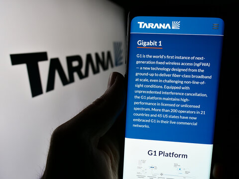 Stuttgart, Germany - 03-28-2024: Person holding cellphone with webpage of US telecommunications company Tarana Wireless Inc. in front of logo. Focus on center of phone display.