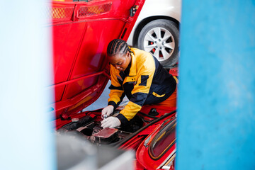 Diversity mechanic teamwork, an African woman in yellow and blue uniforms inspects the opened radiator hood customer car engine. Automobile repairing service. Vehicle maintenance. Professional service - 781868827