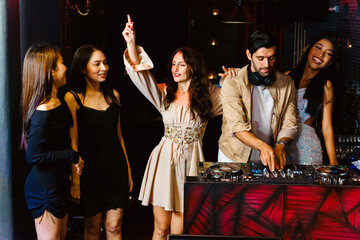 Group of energetic women dancing friends with DJ enjoying night party. Young women dance in the nightclub. Nightlife, disco dance and girl's night party concept. Fun music festival - 781869243