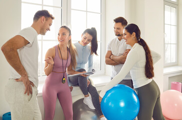 Health centre and fitness club sporty people talking with slim female coach. Discuss how to improve results, overall health and wellness by participating in fitness games, strength training, exercises - obrazy, fototapety, plakaty