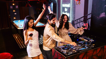 Group of energetic women dancing friends with DJ enjoying night party. Young women dance in the...