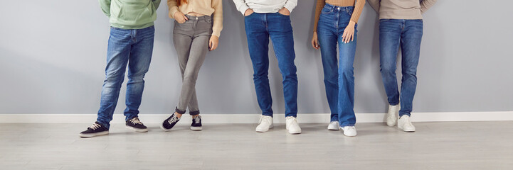 Legs close up, people wearing jeans in easy pose standing, lower body portrait. Friends in trousers...