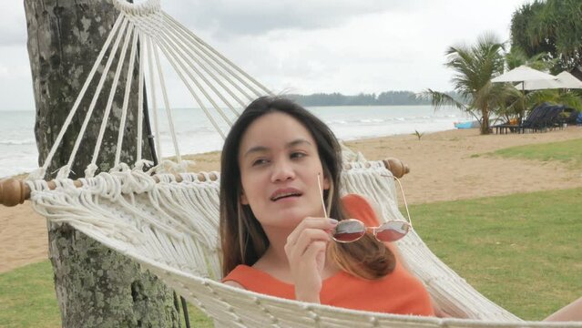 asian woman relaxing and  on hammock near beach under coconut tree in vacation holiday time