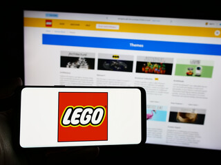 Fototapeta premium Stuttgart, Germany - 04-02-2024: Person holding smartphone with logo of Danish construction toy company LEGO AS in front of website. Focus on phone display.