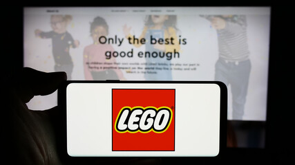 Fototapeta premium Stuttgart, Germany - 04-02-2024: Person holding cellphone with logo of Danish construction toy company LEGO AS in front of business webpage. Focus on phone display.