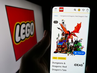 Fototapeta premium Stuttgart, Germany - 04-02-2024: Person holding cellphone with webpage of Danish construction toy company LEGO AS in front of business logo. Focus on center of phone display.