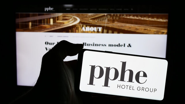 Stuttgart, Germany - 04-04-2024: Person holding smartphone with logo of British hospitality company PPHE Hotel Group Limited in front of website. Focus on phone display.
