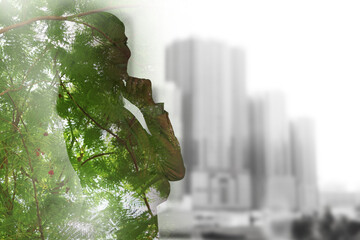 Double exposure of businesswoman and green tree in city