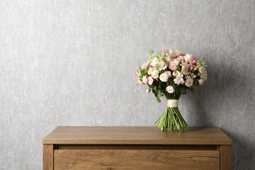 Beautiful bouquet of fresh flowers on wooden table near grey wall, space for text