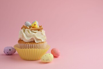 Tasty Easter cupcake with vanilla cream and candies on pink background, space for text