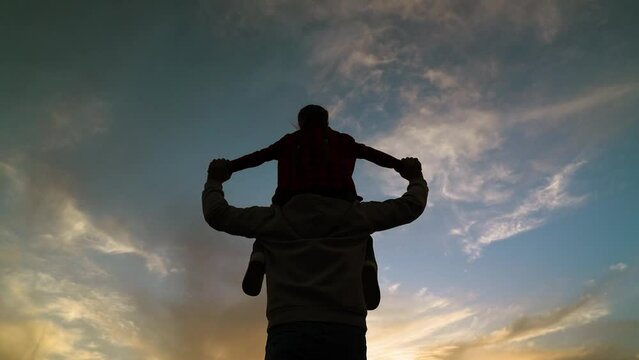 happy family child kid baby girl plays on her father shoulders sunset, child feeling free, joyful kid shoulders, silhouetted parenting, family play silhouette, loving family silhouette, sun setting