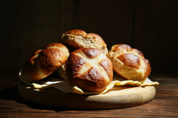 Tasty hot cross buns on wooden table against dark background, closeup