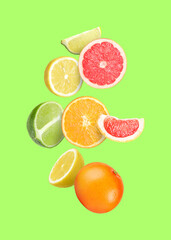 Many different fresh citrus fruits in air on light green background