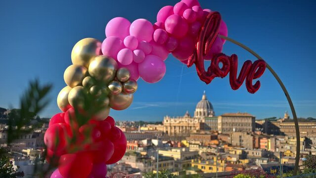 Pink, red and gold, love balloon arch at panoramic view of Vatican City, Rome, Italy.