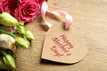 Happy Mother's Day. Heart shaped greeting label and beautiful flowers on wooden table