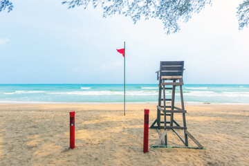 Sea beach with lifeguard wooden chair. and red flag.