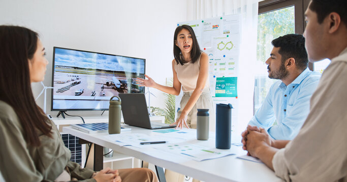 Asian woman lead young group of multiethnic businesspeople in team meeting, using laptop computer presentation on Solar cell panel usage in Airport. Sustainable business, people work at home concept