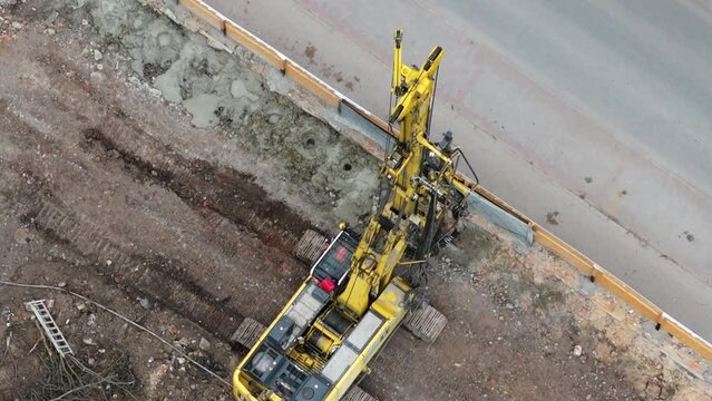 Tracked construction drill rig strengthens unstable, swampy ground by boring holes for concrete foundation pillars.