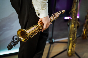 Musician in suit trousers holding brass wind instrument at concert
