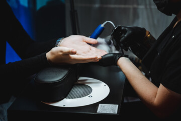 A man with a black mask is painting a womans nails
