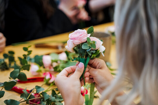 Woman happily arranging cut flowers into a beautiful bouquet for an event