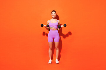 Fototapeta na wymiar Full body young fitness trainer instructor woman sportsman wears top shorts purple clothes train in home gym hold in hand dumbbell isolated on plain orange background. Workout sport fit abs concept.
