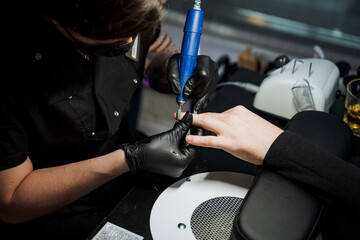 A man is using an automotive tire machine on a womans nails