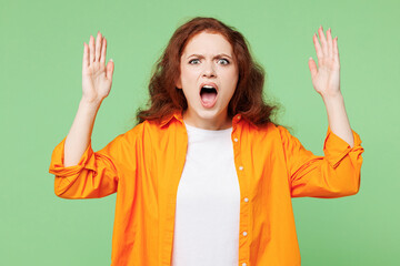 Young indignant mad ginger woman she wear orange shirt white t-shirt casual clothes look camera spread hands scream shout look camera isolated on plain pastel light green background Lifestyle concept