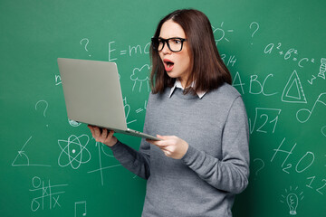 Young shocked mad sad smart IT teacher woman wear grey casual shirt glasses use laptop pc computer...