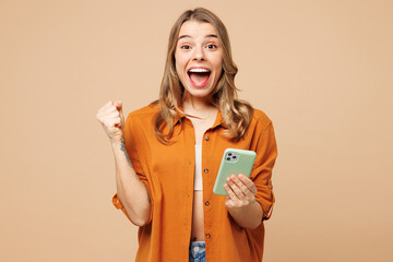 Young happy Caucasian woman she wear orange shirt casual clothes hold in hand use mobile cell phone...