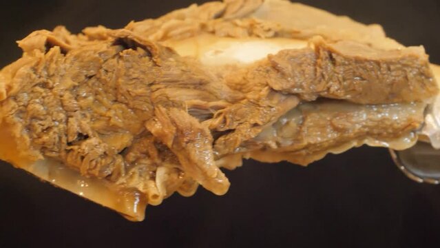 갈비탕의 커다란 갈빗대에 붙어있는 살코기를 잘라 국물에 넣어 당면과 고기를 들어올리는 모습