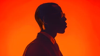 Poster Silhouette of a man in glasses against orange backdrop with tints and shades © Nadtochiy