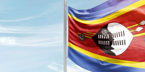 Eswatini national flag with mast at light blue sky.