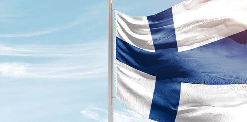 Finland national flag with mast at light blue sky.