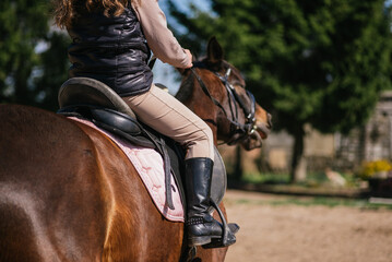 Girl practicing on horseback, riding training boots and horse saddle visible