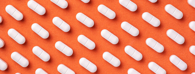 Orange and red medicine background with white pills and tablet, macro.