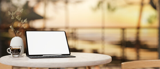 A digital tablet mockup on a round table with a blurred background of a sunset beach view.
