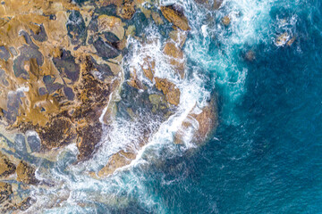 waves breaking on the rocks of the coast, aerial top view with a drone.