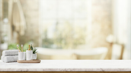 Toiletries on a luxury white marble tabletop with a blurred background of a luxury bathroom.