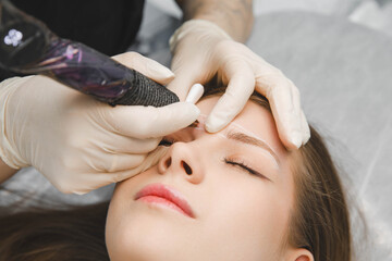 A cosmetologist applies permanent makeup to the eyebrows - eyebrow tattoo. eyebrow perm
